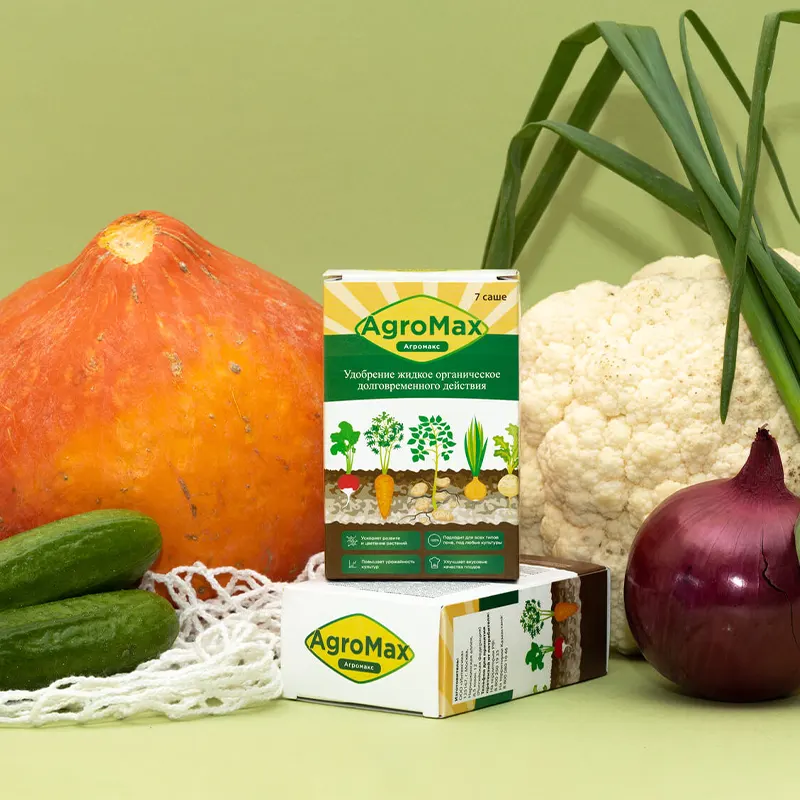 Две коробки Агромакс на зелёнём фоне в окружении овощеей и зелени