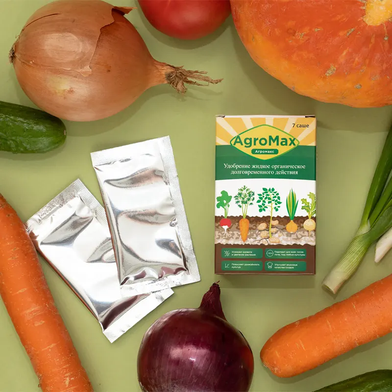 Картонная коробочка удобрения Агромакс и два пакетика лежат на столе в окружении овощей