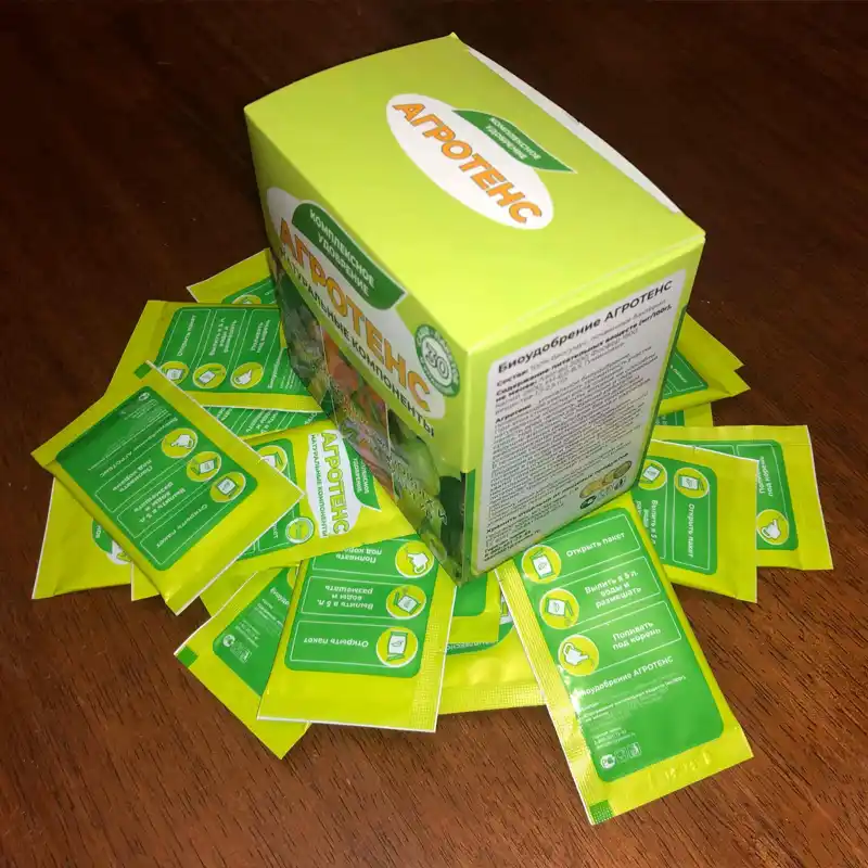Коробка Агротенс стоит на куче пакетиков с удобрением