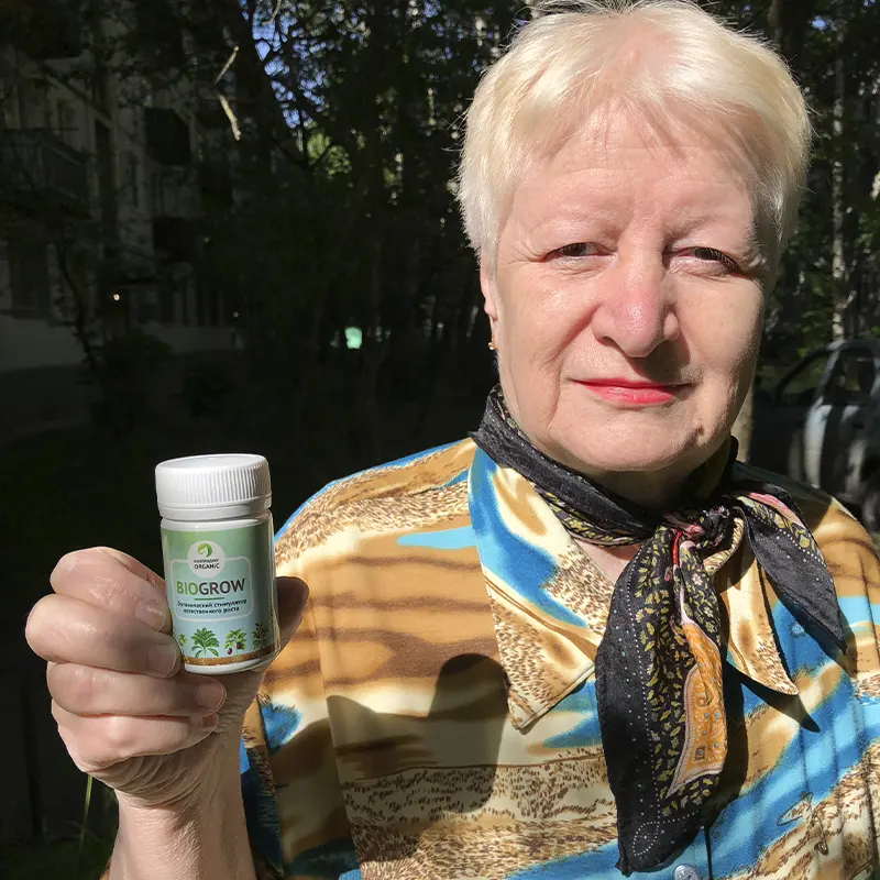 Пенсионерка держит в руке баночку удобрения BioGrow