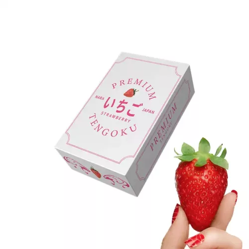 Японская клубника Тэнгоку в упаковке и рука держащая плод клубники