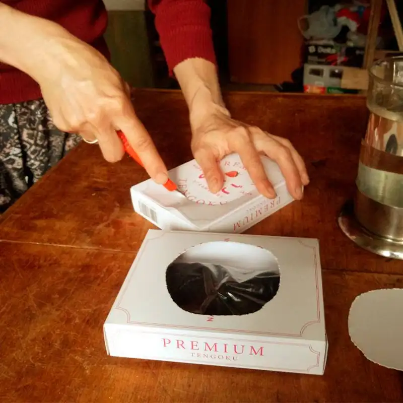 Женщина вырезает в упаковке отверстие для прорастания клубники