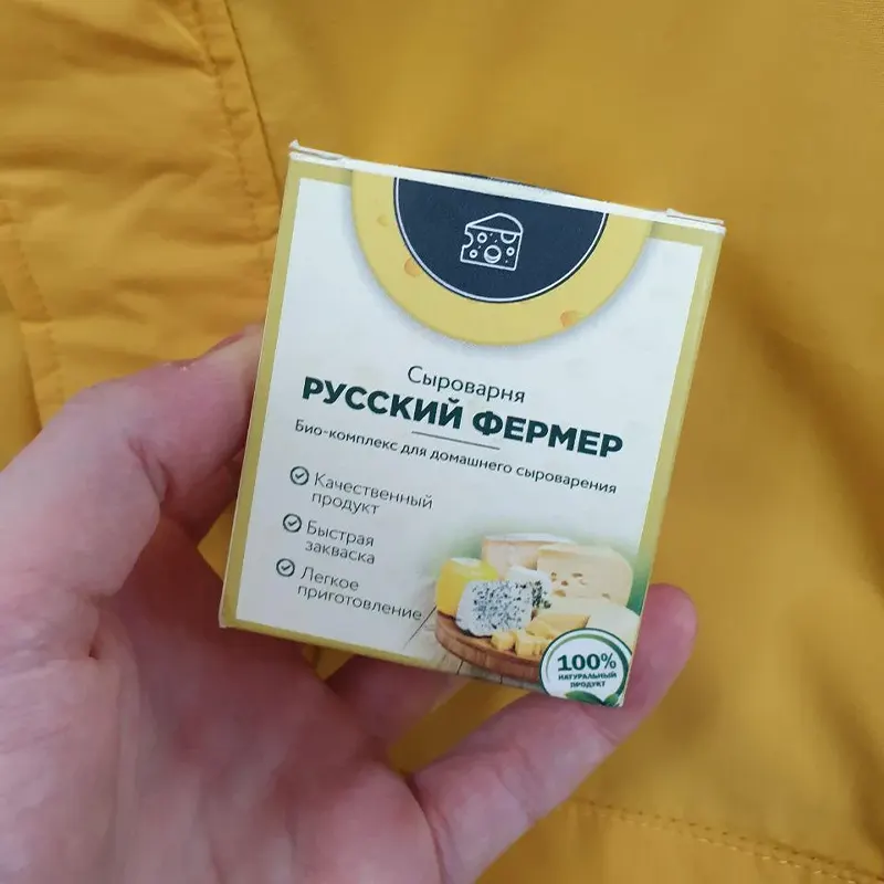 Рука держит упаковку закваски для сыра Русский фермер