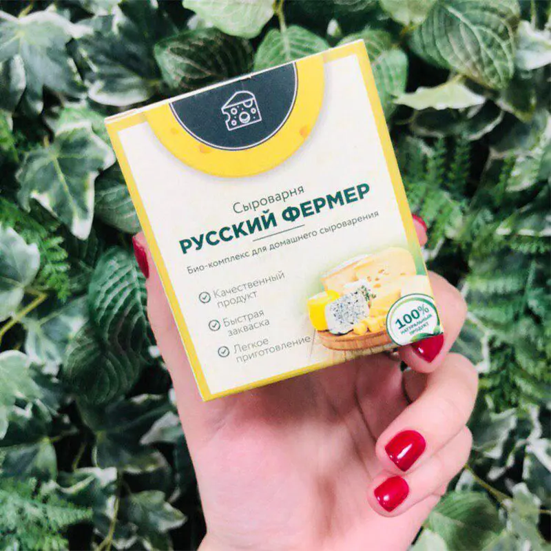 Рука держит упаковку закваски Русский фермер на фоне листвы