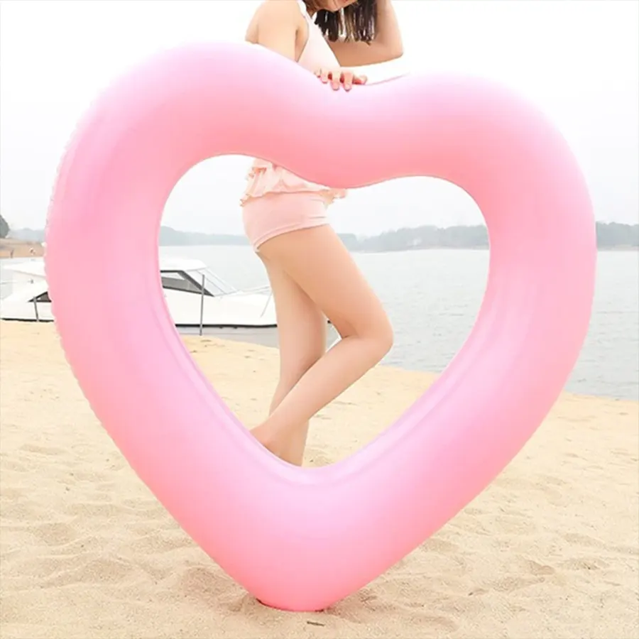 Розовое надувное сердце на фоне девушки на пляже