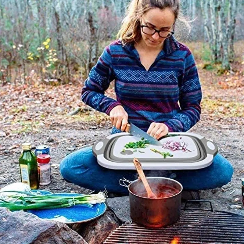 Женщина готовит на складной разделочной доске на природе