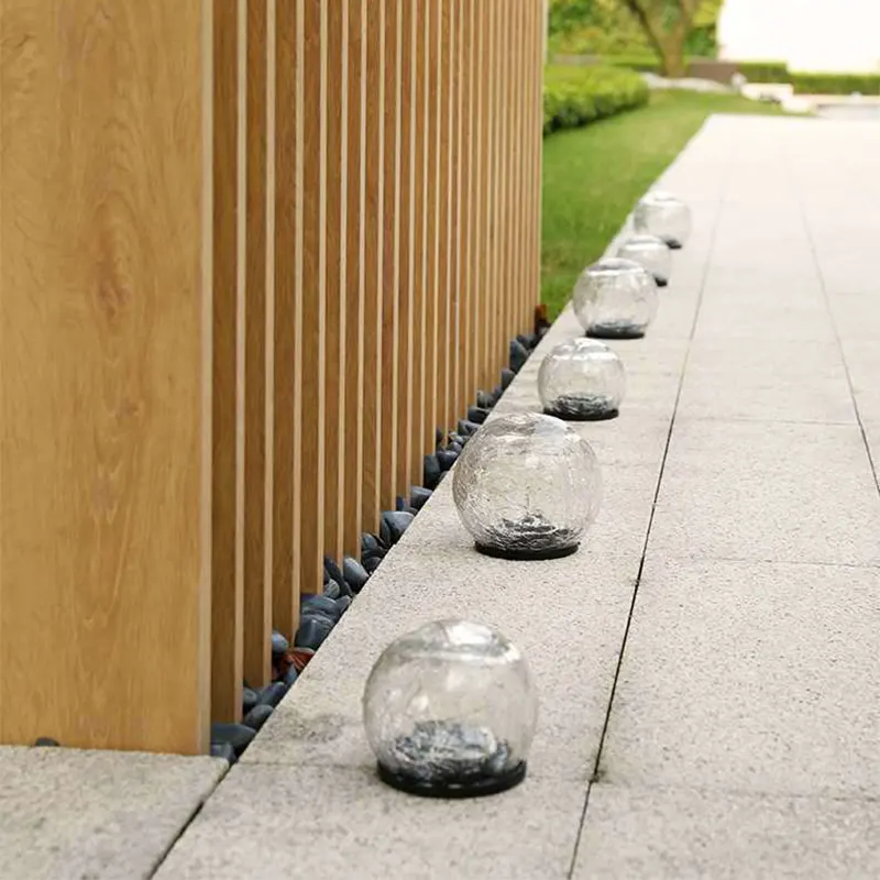 Светильники-шары для сада стоят на плитке днём