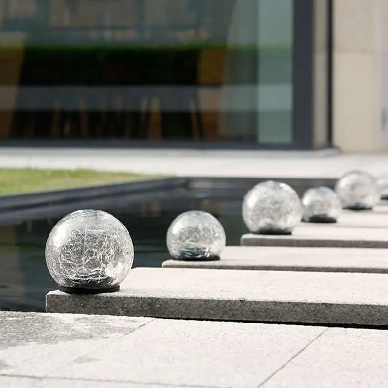 Садовые фонари шары стоят в ряд рядом с бассейном