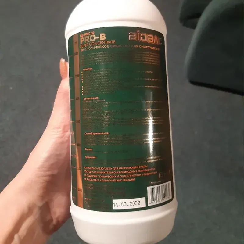 Рука держит бутылка средства для септиков Биобак