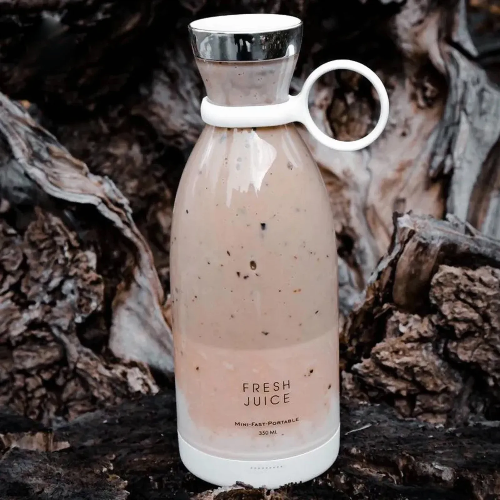 Блендер 'FRESH JUICE' с коричневатым смузи на фоне природы с мхом и ветками.